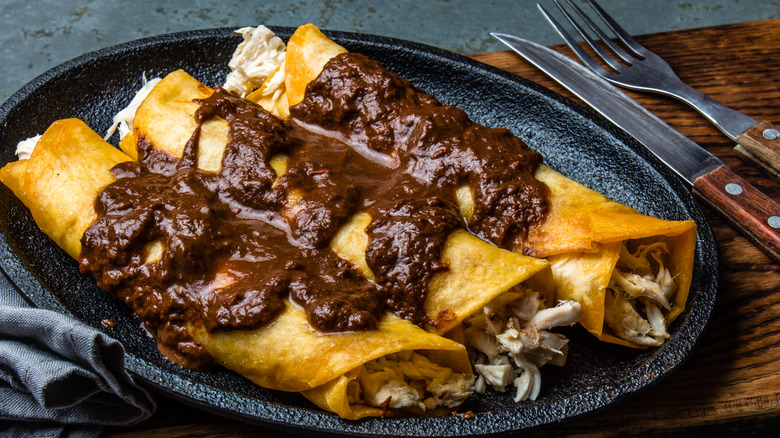 Chicken mole enchiladas on black plate