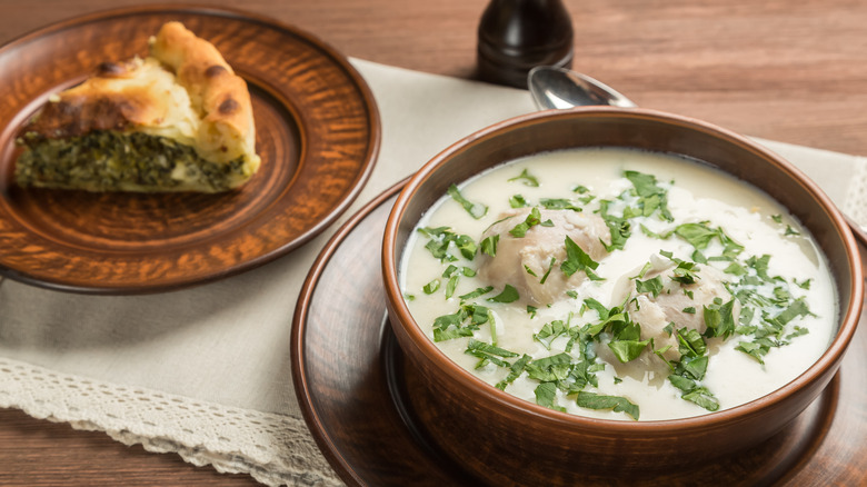 Bowl of avgolemono soup with plate of spanakopita