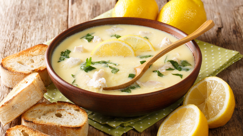 Bowl of avgolemono soup with lemon and bread