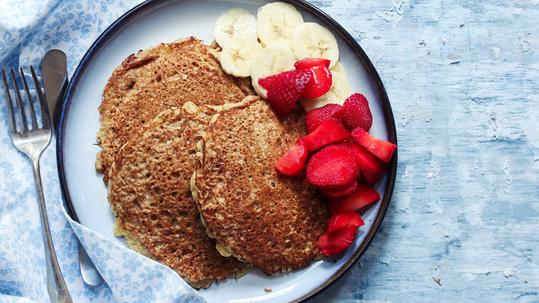 Oat bran pancakes with fruit on plate with blue background