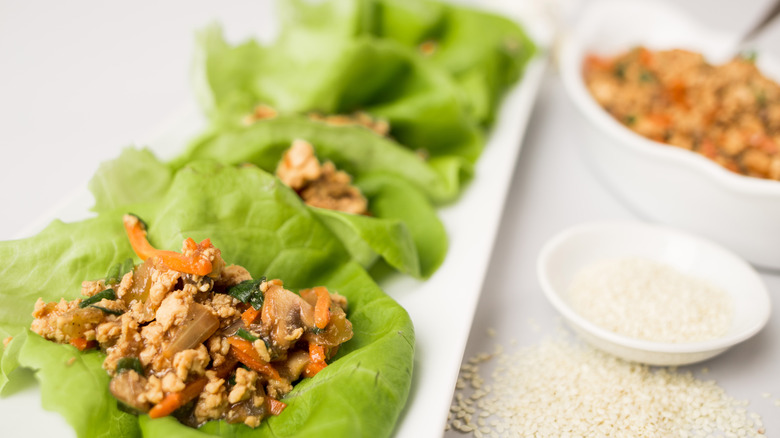 White plate with lettuce wraps filled with meat