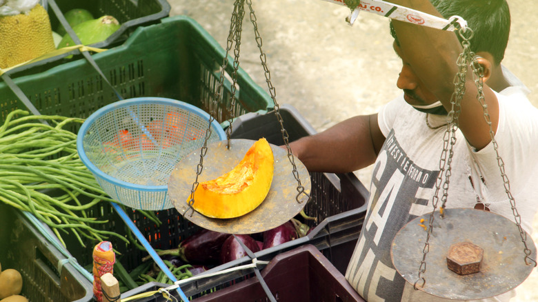 man weighing calabaza squash