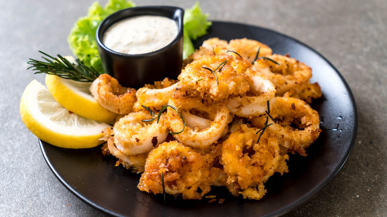 fried calamari on plate with sauce and lemon