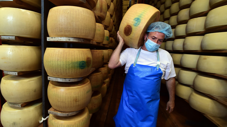 Cheese maker lugging wheel of parmesan