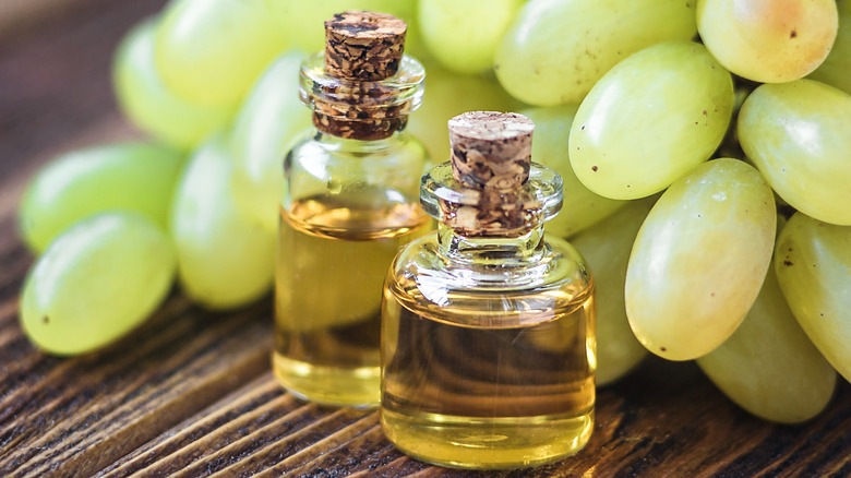 Two bottles of champagne vinegar in front of a bunch of grapes