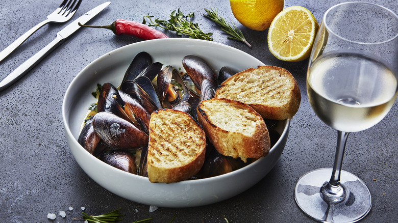 Mussels and bread next to glass of white wine