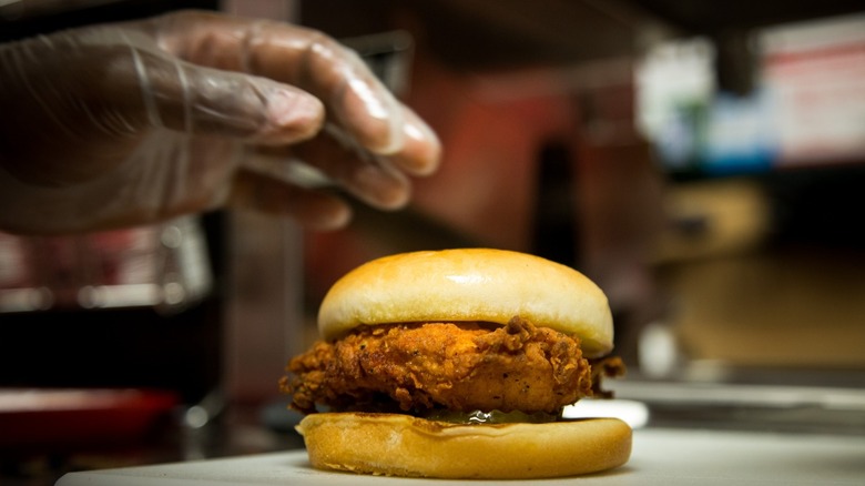 Hand hovering over a fried chicken sandwich