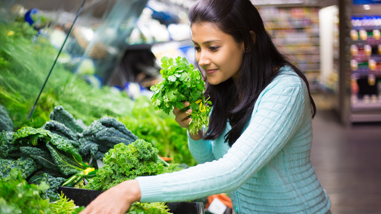 Woman choosing cilantro in store