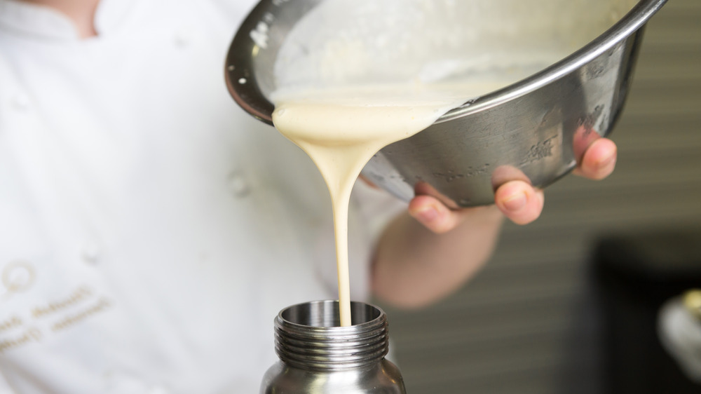 Pouring cream from a metal bowl