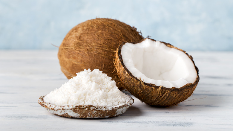 Coconut flour in bowl next to open coconut