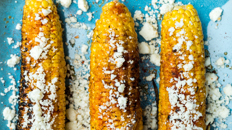 Three ears of Mexican street corn with cotija sprinkled on top