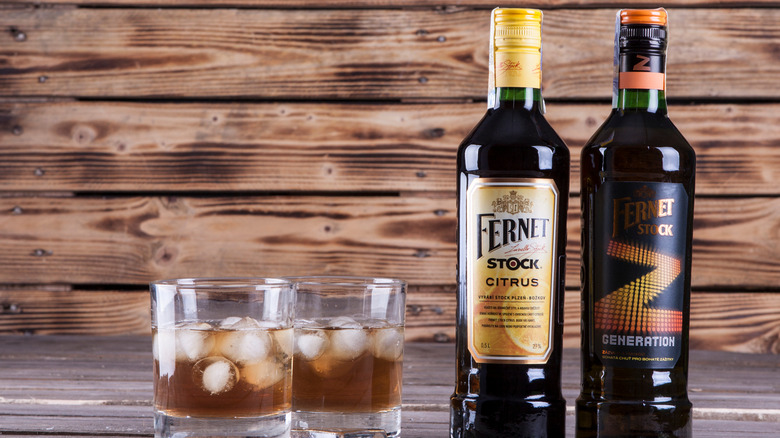 Two bottles of Fernet next to two glasses with liquor and ice
