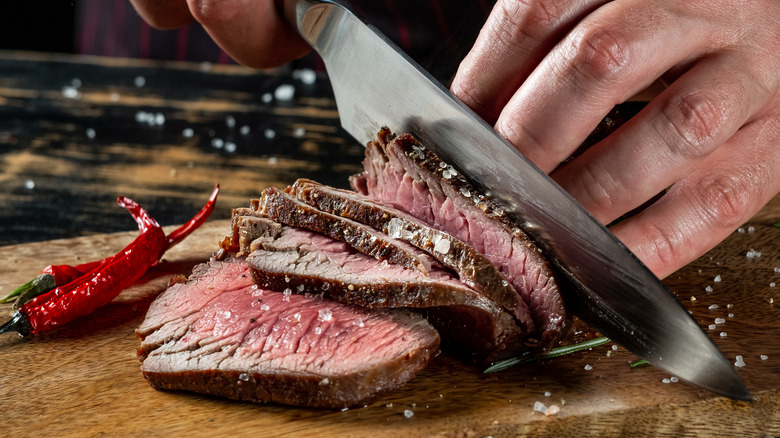 Coarse salt on steak that is being sliced 