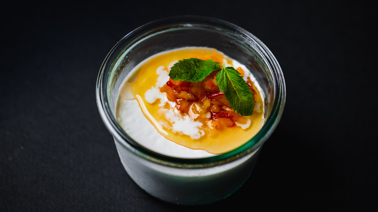 Flummery topped with honey in a glass jar on a black background