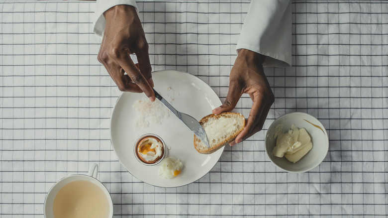 Person spreading butter on bread