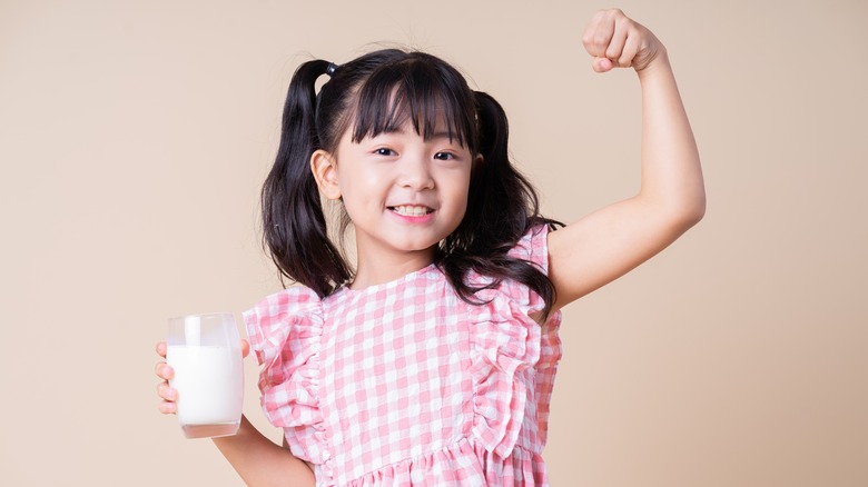 Girl flexing and holding glass of milk