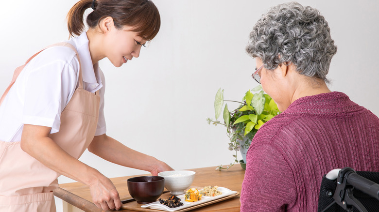 woman bringing food to elder in care