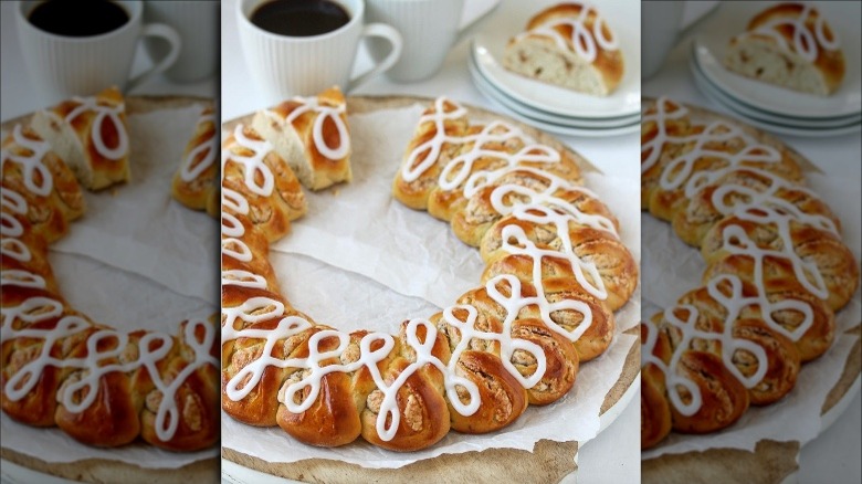 Kringle with slice cut out alongside coffee cups