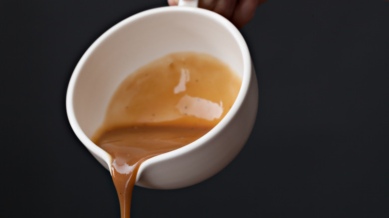 Brown gravy pouring from cup