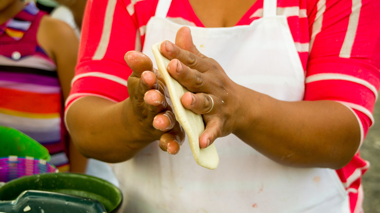 Person turning masa into a tortilla