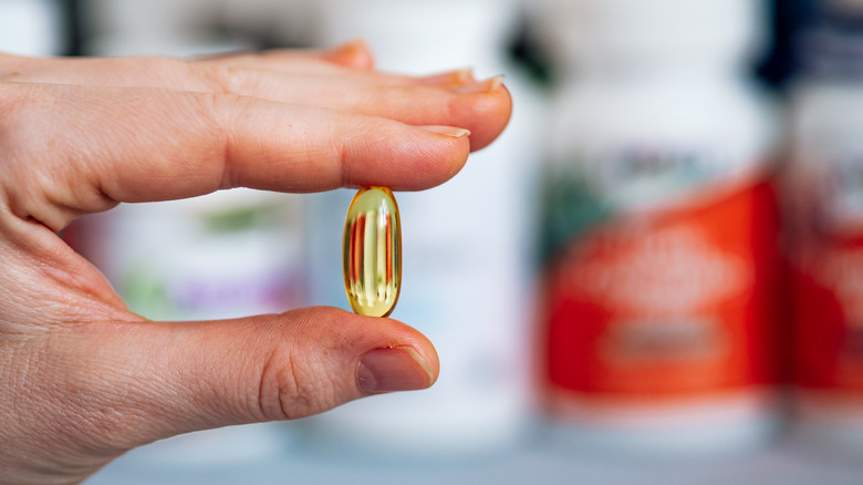 Hand holding a translucent MCT oil supplement