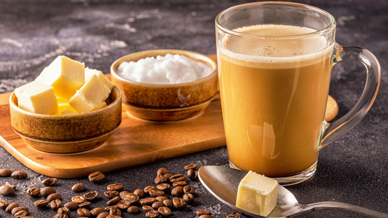 Butter coffee in a glass mug next to coffee beans and butter