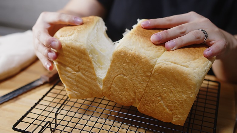 Hands pulling apart a milk bread loaf