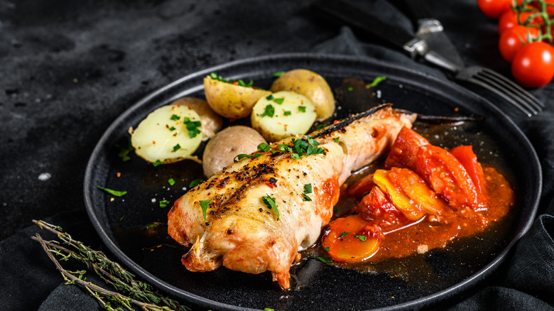 Roast monkfish on a plate with tomatoes and potatoes