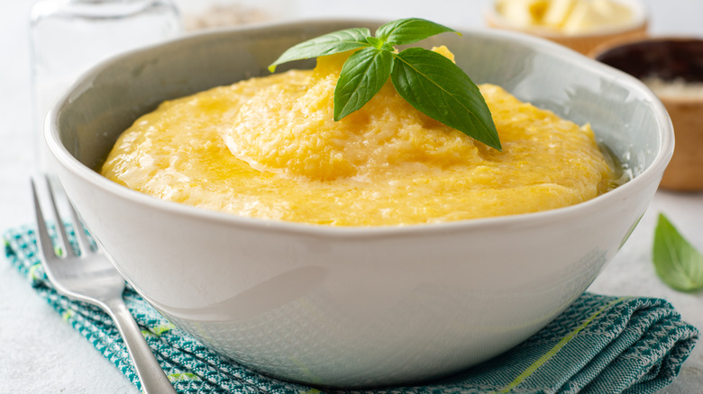 Side view of polenta in white bowl next to fork