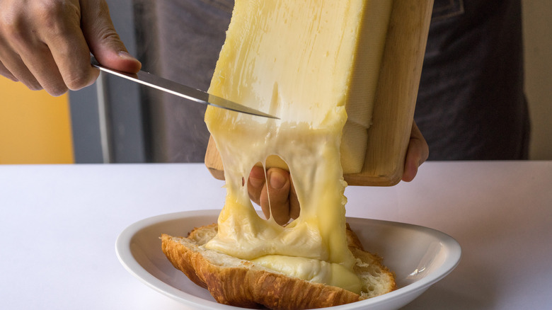 Hot raclette scraped onto croissant