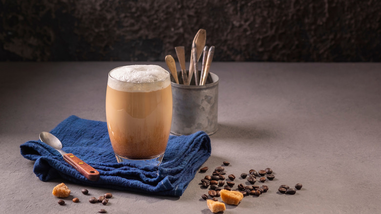 A glass of Raf coffee with coffee beans scattered around