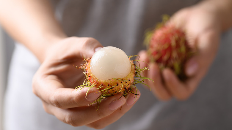 Hand holding a half peeled rambutan