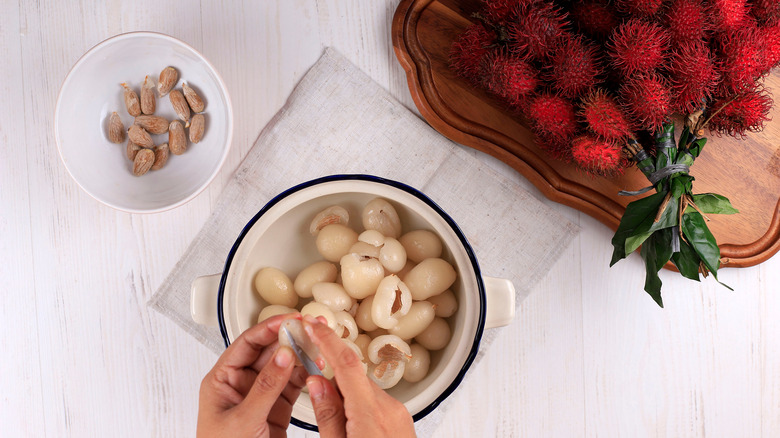 Person separating rambutan seeds with a knife