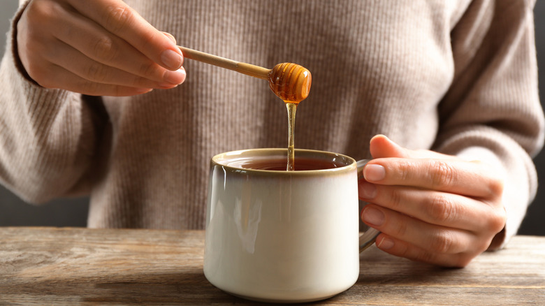 Woman adding honey to tea