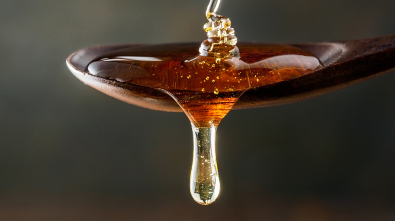 Honey dripping from a wooden spoon