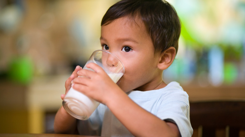 A small boy drinking a glass of milk