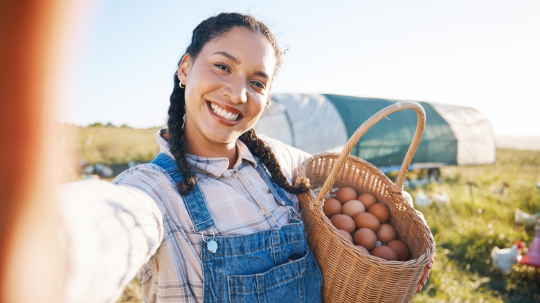 A homesteader taking a selfie with eggs in a basket