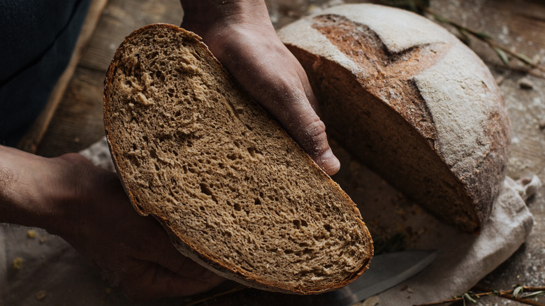 Baker's hands holding rye loaf