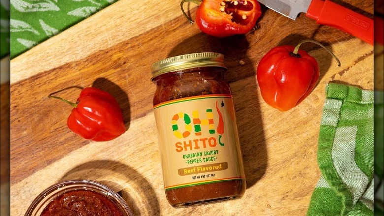 Jar of Oh Shito! sauce with hot peppers on wooden background