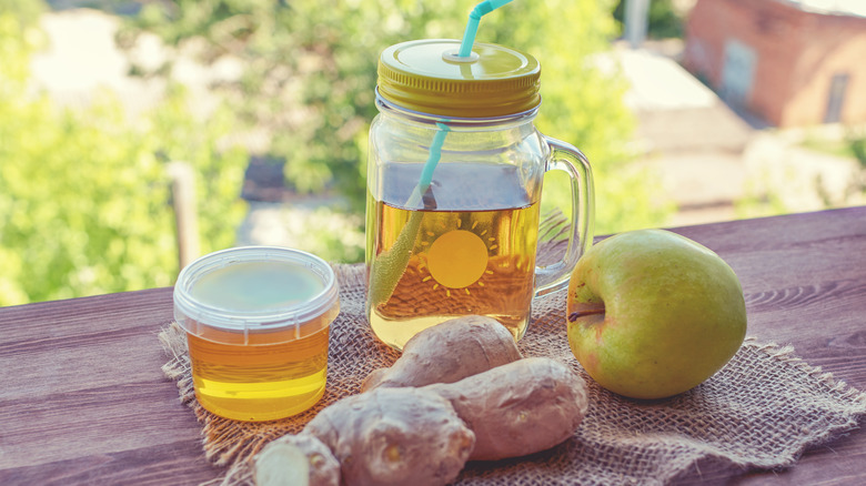 switchel in mason jar next to ginger and apple