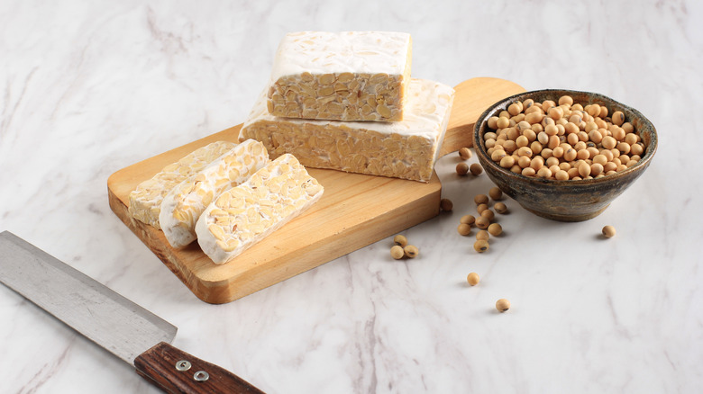 Cutting board with tempeh and bowl of soybeans