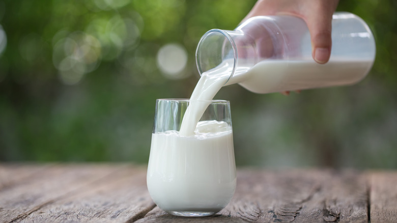 hand pouring milk into glass