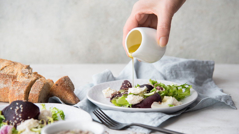 Person pouring oil on salad