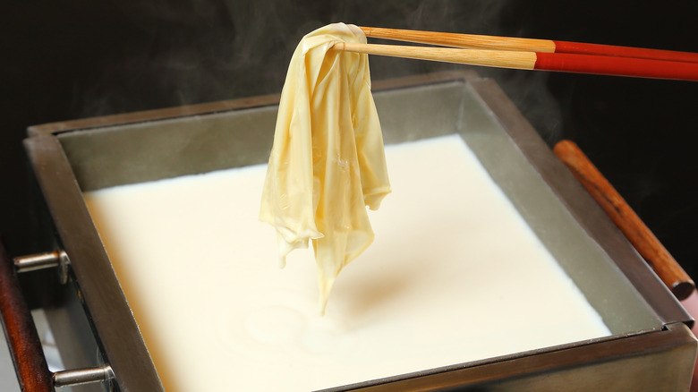 A sheet of yuba hanging on top of soy milk