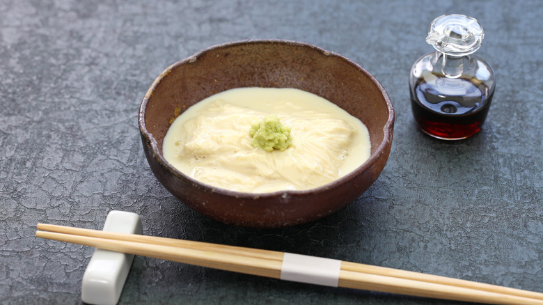 A bowl of yuba sashimi with chopsticks, soy sauce and wasabi