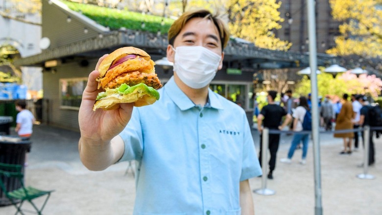 Junghyun holding a Atoburger in front of Madison Square Park's Shake Shack