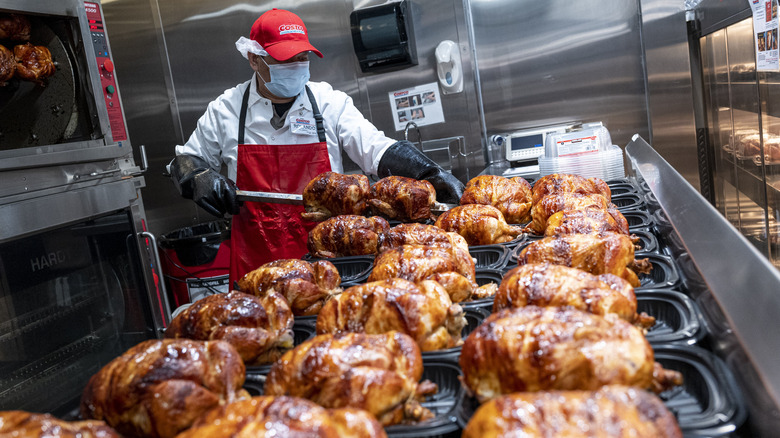 Costco worker placing rotisserie chickens into plastic carriers