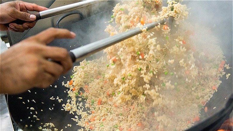 Person tossing fried rice wok