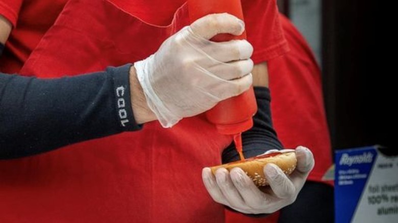 A Five Guys staff making a hamburger