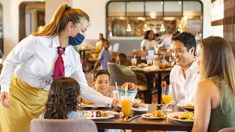 a table full of happy guests and a server at a disney world restaurant